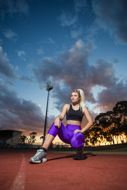 Female sprinter athlete getting ready to start a race on a tartan racetrack.