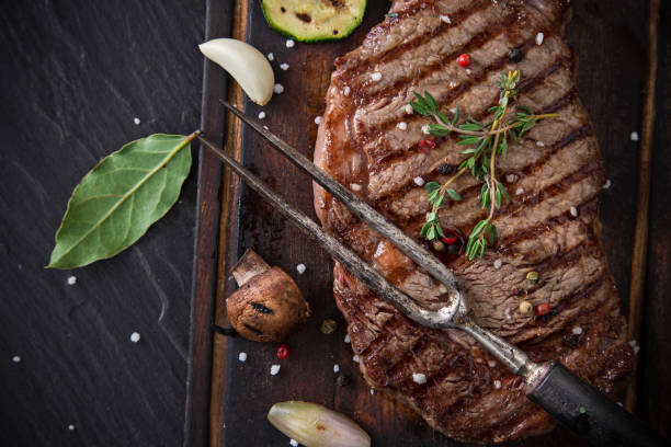 delicioso bife na mesa de pedra preta - strip steak steak barbecue grill cooked - fotografias e filmes do acervo