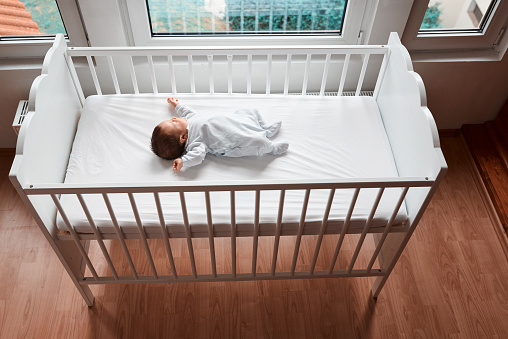 high angle view of cute baby girl sleeping in her bed, photo taken indoors.