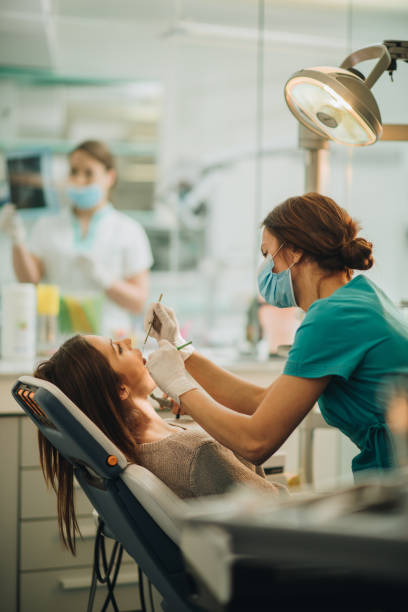 mulher jovem, tendo os dentes verificados durante a consulta no dentista no consultório do dentista. - dentist dentist office human teeth dental equipment - fotografias e filmes do acervo