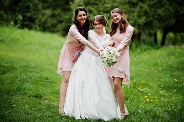 istock Attractive bride posing and having fun with two her bridesmaids in the park on a sunny spring wedding day. 860446688