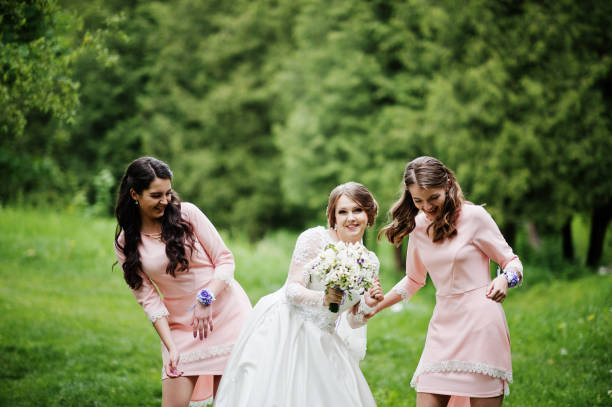 istock Attractive bride posing and having fun with two her bridesmaids in the park on a sunny spring wedding day. 860446960