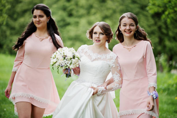 istock Attractive bride posing and having fun with two her bridesmaids in the park on a sunny spring wedding day. 860447104