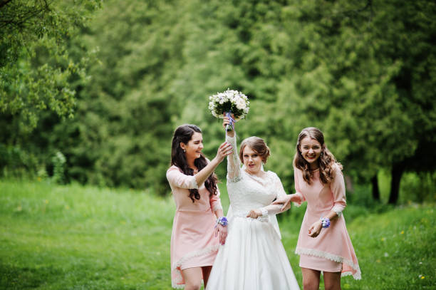 istock Attractive bride posing and having fun with two her bridesmaids in the park on a sunny spring wedding day. 860447272