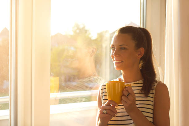 istock Girl with cup of coffee beside window 860450464