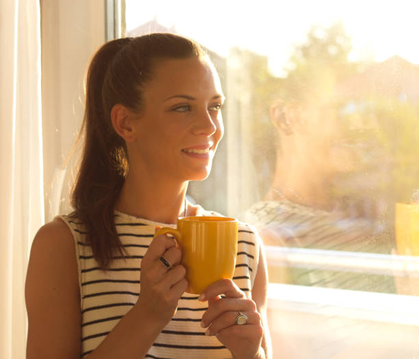 istock Girl with cup of coffee beside window 860450492