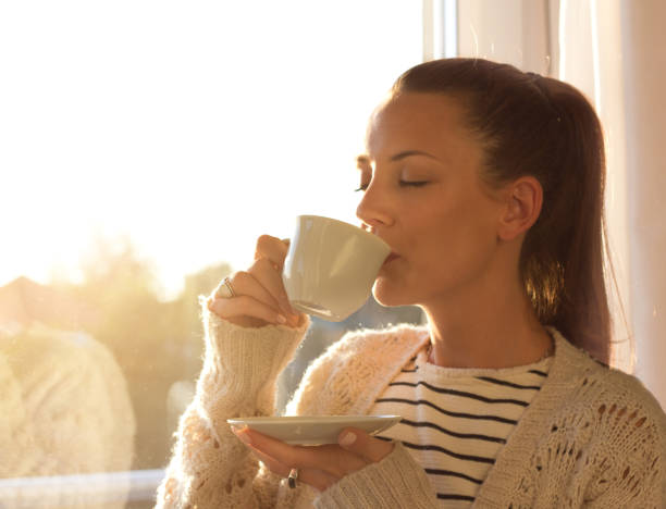 istock Girl with cup of coffee beside window 860450540