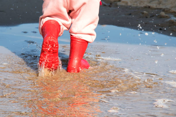 istock wellingtons in puddle.kid rubber boots in the sea background 860454744