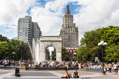 New York, New York, USA - July 3, 2017: People enjoy some street performance in the Washington square park in the heart of Manhattan on a sunny summer Sunday in New York City.