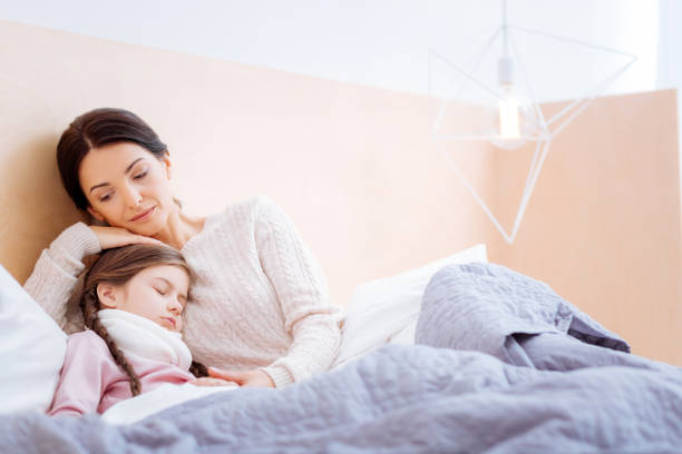 Loving mother hugging her ill sleeping child