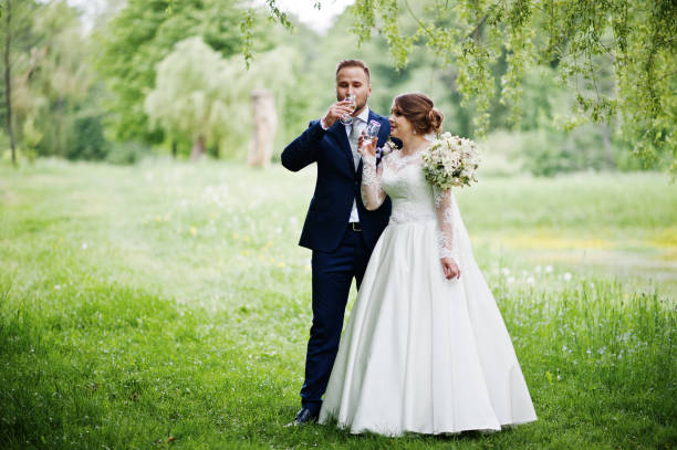 istock Newly married wedding couple drinking champagne in forest or park. 860458908