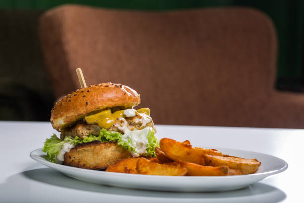 istock Tasty chicken burger with wedges, on a white plate 860458956