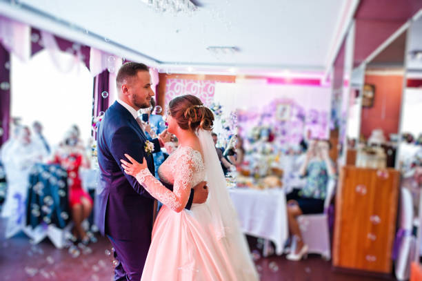 istock Beautiful wedding couple performing their first dance in the restaurant with different lights and bubbles and guests on the background. 860459002