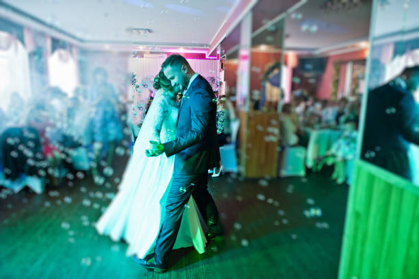 istock Beautiful wedding couple performing their first dance in the restaurant with different lights and bubbles and guests on the background. 860459006