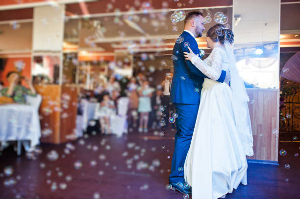 istock Beautiful wedding couple performing their first dance in the restaurant with different lights and bubbles and guests on the background. 860459040