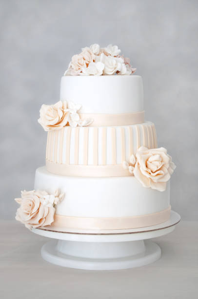 istock White wedding cake decorated with flowers on a white wooden table. 860463288