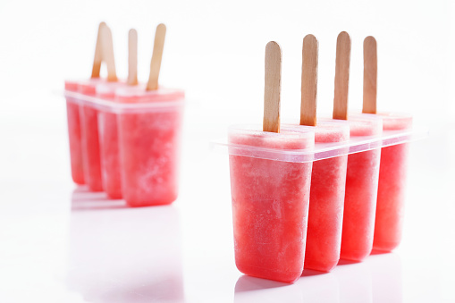 Homemade watermelon popsicles on white marble background