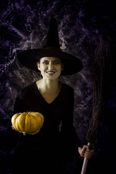 istock Halloween Witch holding a pumpkin and a broom. 860472322