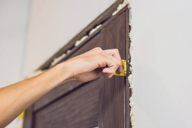 istock Young handyman installing door with an mounting foam in a room 860488156
