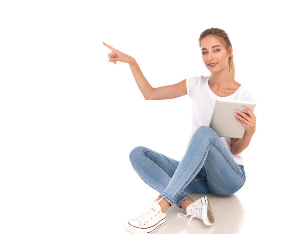 istock seated casual woman with tablet pointing to side 860488204