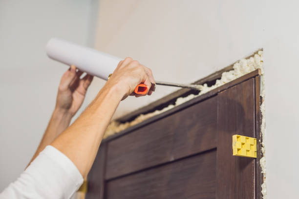 istock Young handyman installing door with an mounting foam in a room 860488228