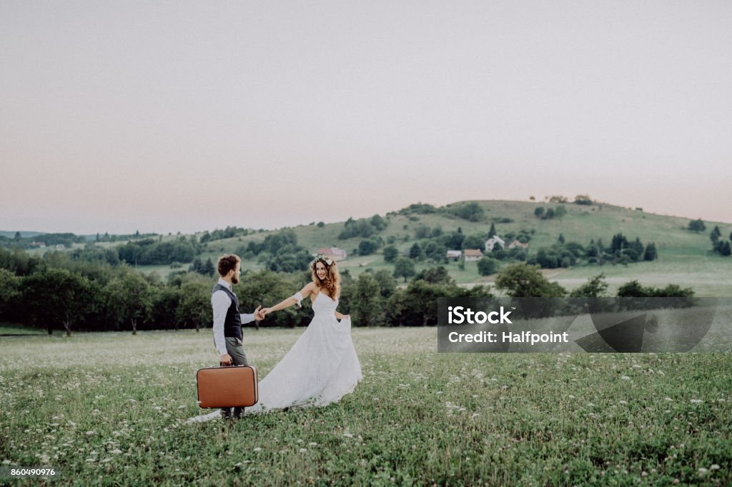 Beautiful bride and groom at sunset in green nature. Beautiful young bride and groom outside in green nature at romantic sunset, holding hands. Bride Stock Photo