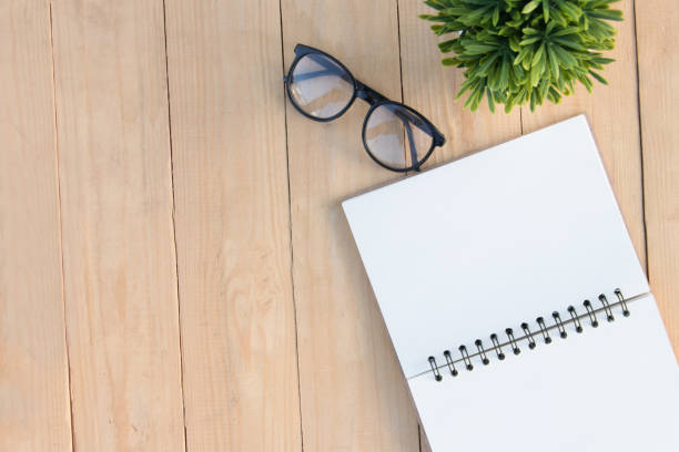istock Empty book and eyeglasses and tree on wooden table copy space, top anlge view, presentation business 860494848