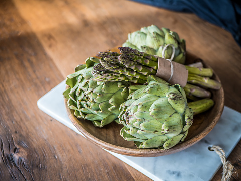 Organic green vegetables food in wood bowl. Asparagus and artichoke on wooden background.
