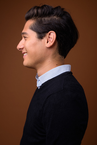 Studio shot of young multi-ethnic handsome man looking smart against colored background vertical shot