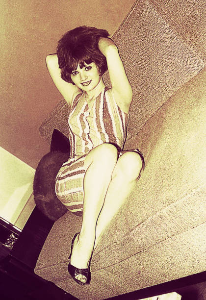 Vintage black and white toned photo from the sixties of a young woman posing sensual at home.