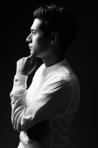 Studio shot of young multi-ethnic handsome man against black background in black and white vertical shot