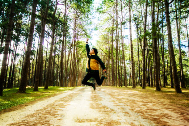 istock People jumping in forest trees sun light background. 860520414