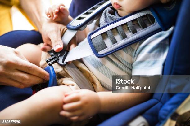 Cinturón De Seguridad De Fijación De Padre A Su Hijo Sentado En El Coche Foto de stock y más banco de imágenes de Bebé