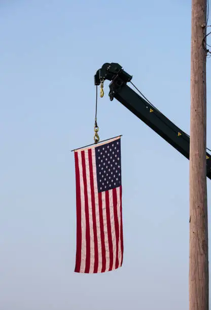 Big American flag hanging from a crane.