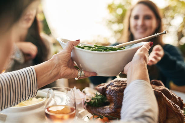 Please pass the beans Shot of a unrecognizable woman passing on a plate of green beans to a cheerful woman at lunchtime over a table serving size stock pictures, royalty-free photos & images