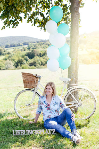 istock Happy Woman sitting at a tree with a vintage bicycle 860537494
