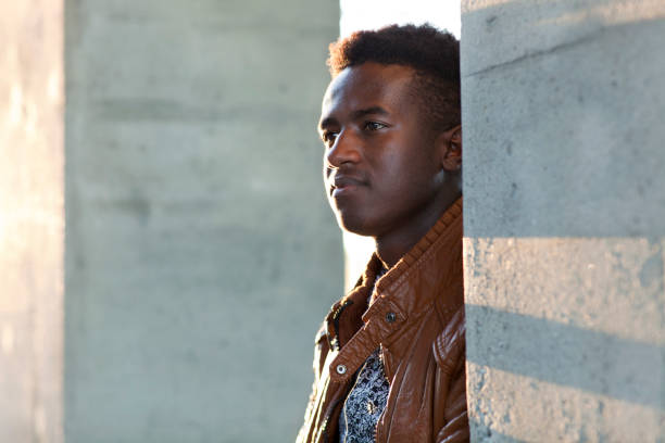 istock Handsome young black man stands in sunlight between concrete pillars 860540924