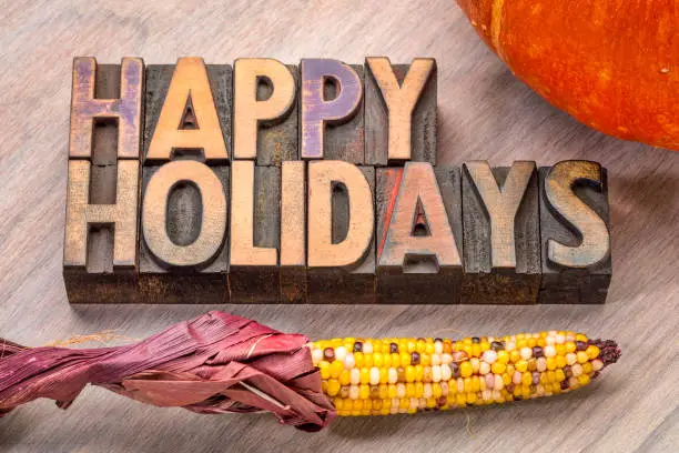 Happy Holidays banner or greeting card in vintage letterpress wood type with pumpkin and corn