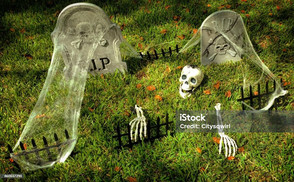 Halloween Decorations of a Skeleton with a Spider on Its Head Climbing Out of a Grave Creepy Halloween decorations of a skeleton with a spider on its head climbing out of a grave with tombstones and spiderwebs on a house's front lawn in the Houston suburb of Clear Lake, Texas. Halloween Stock Photo
