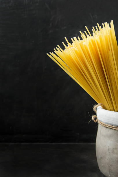 istock Uncooked Spaghetti in Earthen Jar on Black Background. Menu Poster Template Copy Space Text Ready. Mediterranean Healthy Diet. 860571418