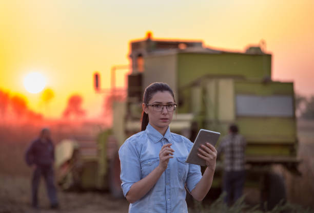 istock Agronomist with tablet and combine harvester 860574376