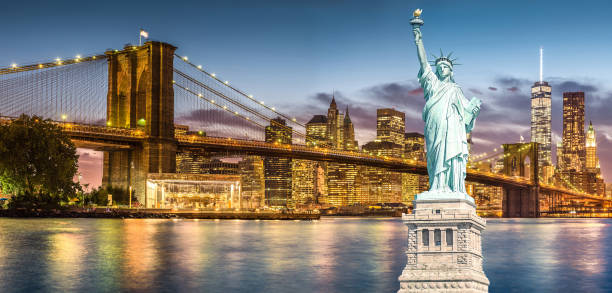 la statua della libertà e il ponte di brooklyn con sfondo world trade center vista tramonto crepuscolare, punti di riferimento di new york city - new york city panoramic statue of liberty skyline foto e immagini stock