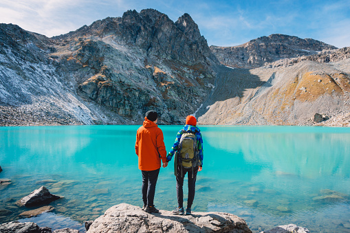 Couple of tourists looks at the lake. Honeymoon in Alps. Beautiful turquoise lake in the mountains.