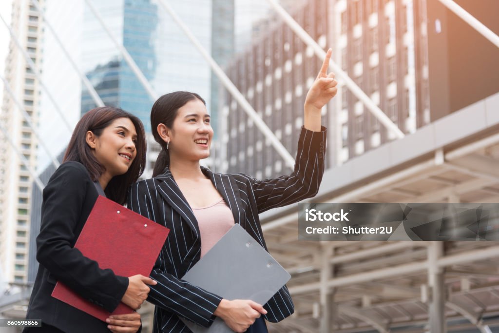 Two young beautiful business women pointing and smiling with outdoor background. Business and beauty concept. Meeting and Greeting concept Adult Stock Photo