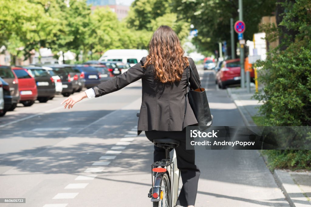 Joven empresaria mostrando a su vez en bicicleta - Foto de stock de Andar en bicicleta libre de derechos