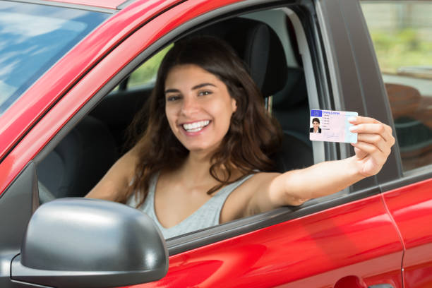 Woman Showing Her Driving License Smiling Young Woman Showing Her Driving License From Open Car Window drivers license stock pictures, royalty-free photos & images