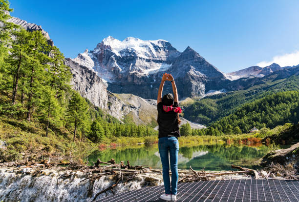 A young woman standing by the lake, Daocheng County, Sichuan province, China.