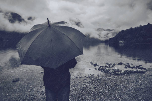 istock Woman with umbrella standing in the rain 860614184