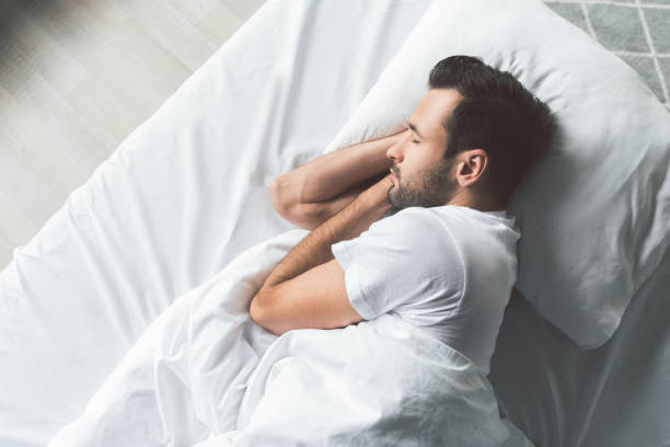 Cute young man sleeping on bed Top view of calm guy napping in his bedroom with enjoyment. Copy space man sleeping on bed stock pictures, royalty-free photos & images