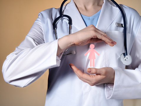 Un médico de la mujer es símbolo de la mujer en sus manos. Mujer médico con un estetoscopio gesticulando sobre fondo beige. photo